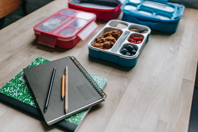 Lunchboxen aus Silikon und Hefte mit Stiften darauf.